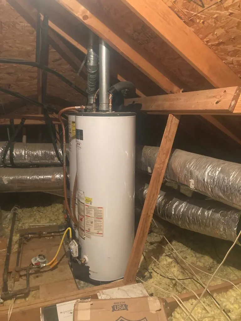 A gas tank water heater installed in an attic on a platform, with its vent and gas line in place.
