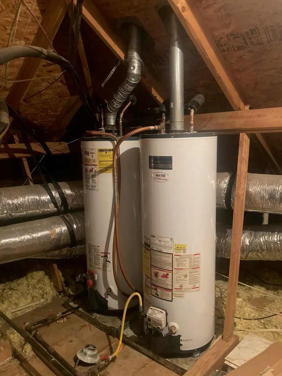 Two gas tank water heaters in an attic, before a tankless conversion.