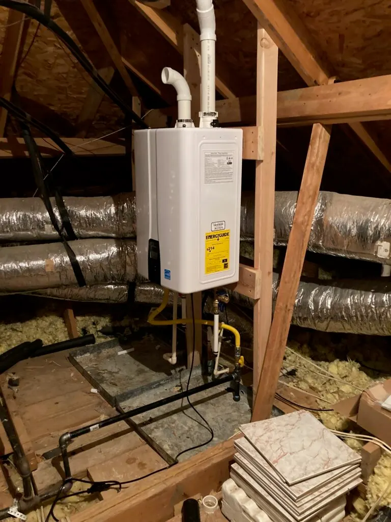 A wall-mounted gas tankless water heater installed in an attic, with new venting through the roof.