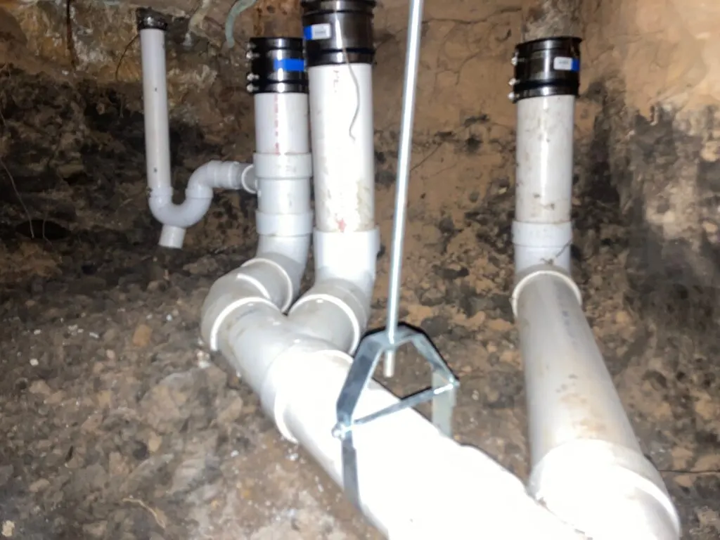 New PVC fittings under a slab where several fixture drains join the main line.